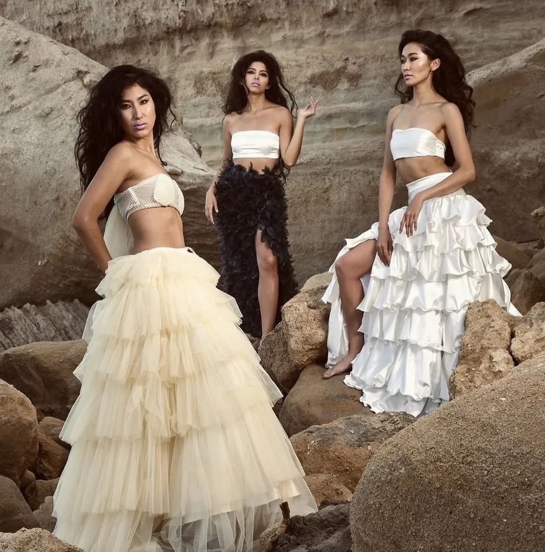 Tres modelos con tules beige, negro y blanco sobre rocas — Dalum